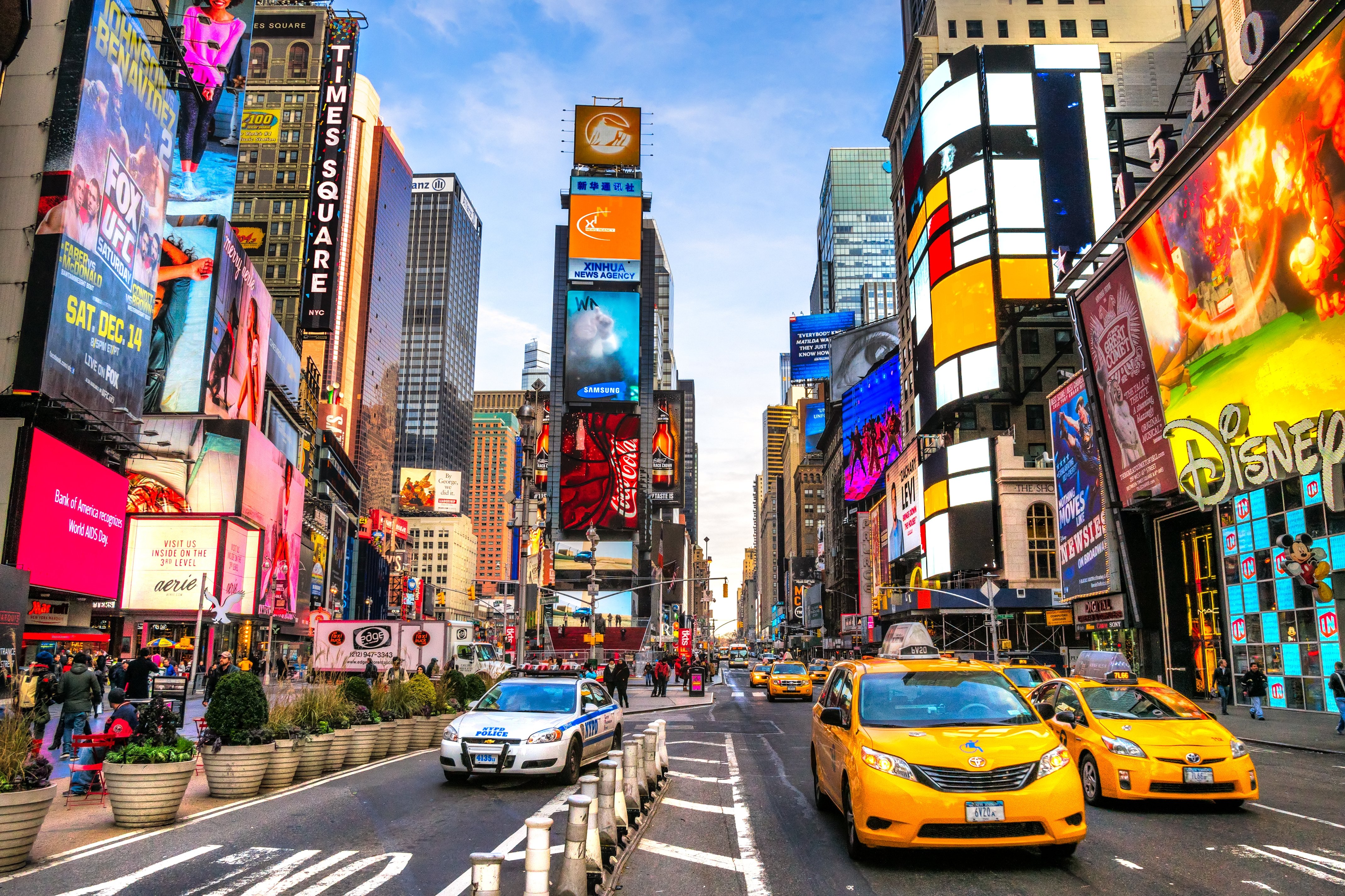 Busy cityscape with bright billboards and yellow taxis in an urban street.