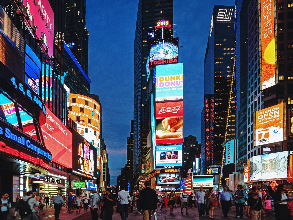 Crowded Times Square at night with bright billboards and advertisements.