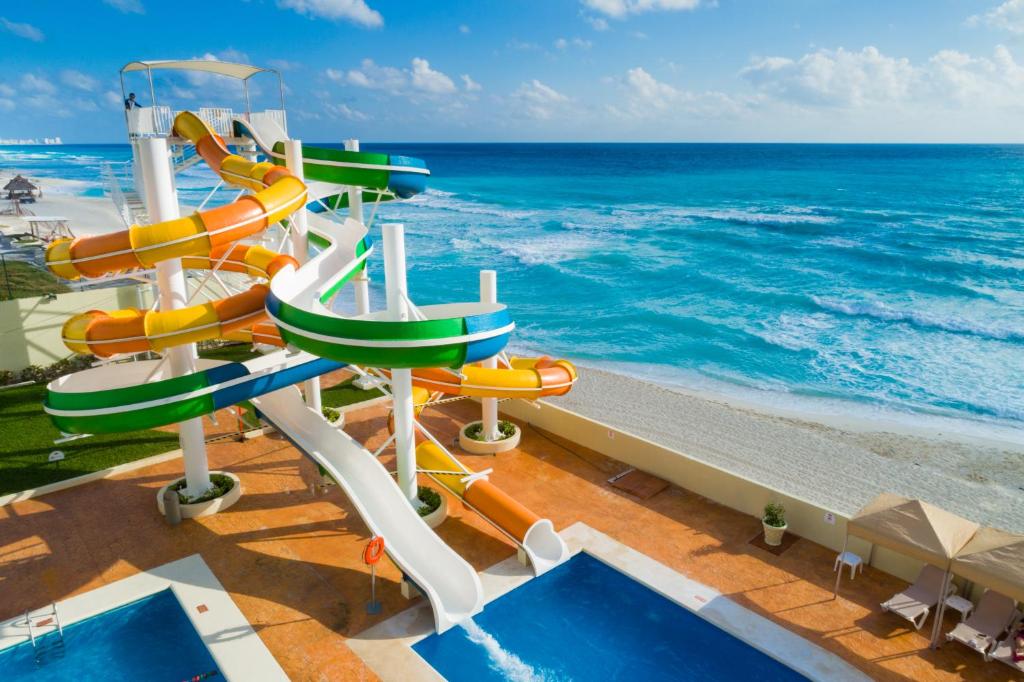 Colorful water slides by a beachside pool with ocean view.
