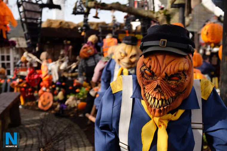 A line of frightening pumpkin-headed figures dressed in costumes for a Halloween display.
