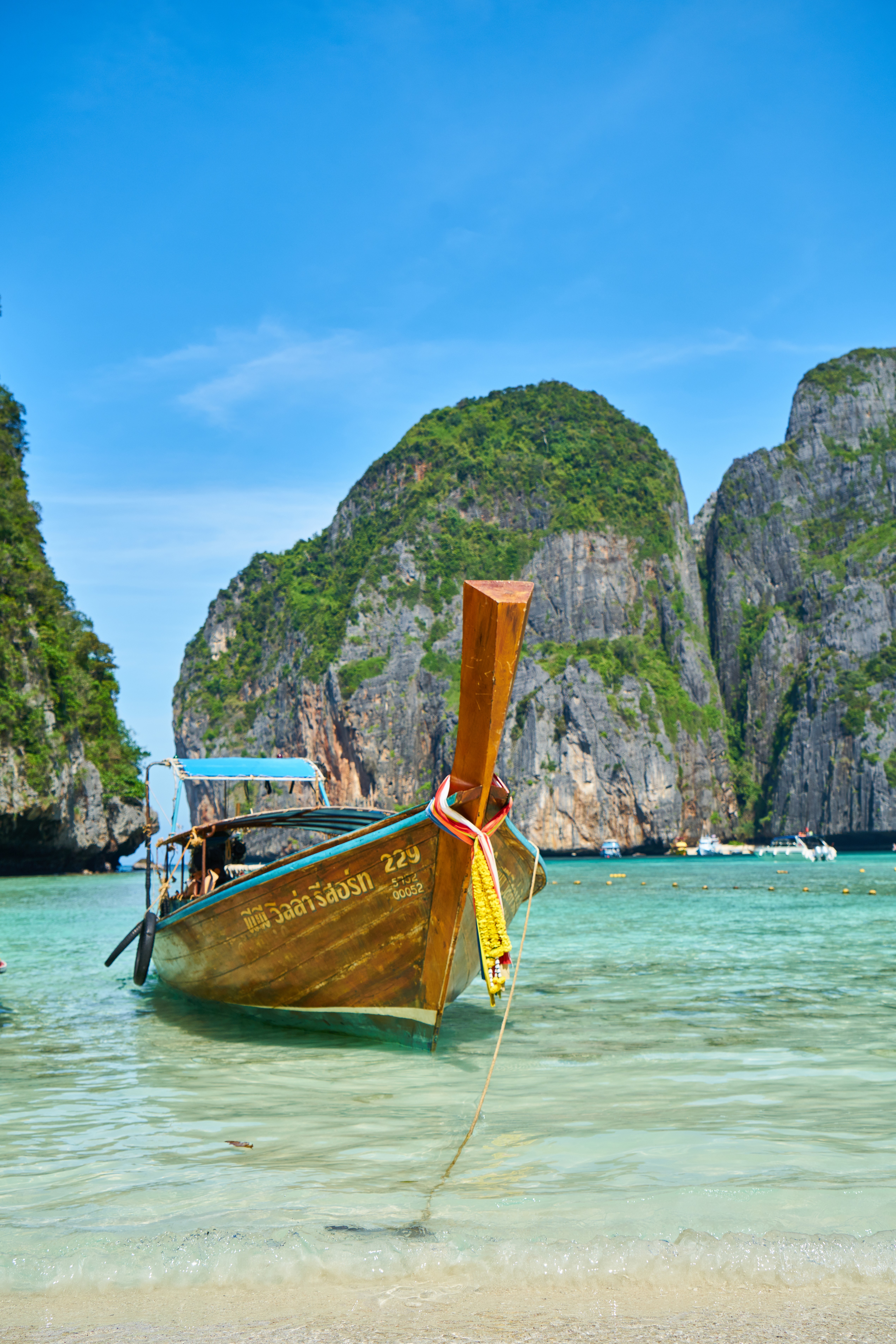 Wooden boat on clear water with rocky cliffs in the background.