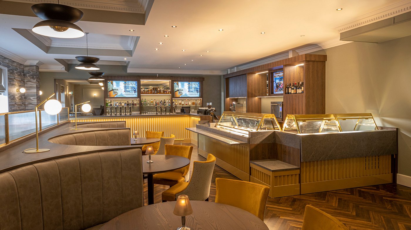 Modern bar interior with curved seating, bar counter, and warm lighting.