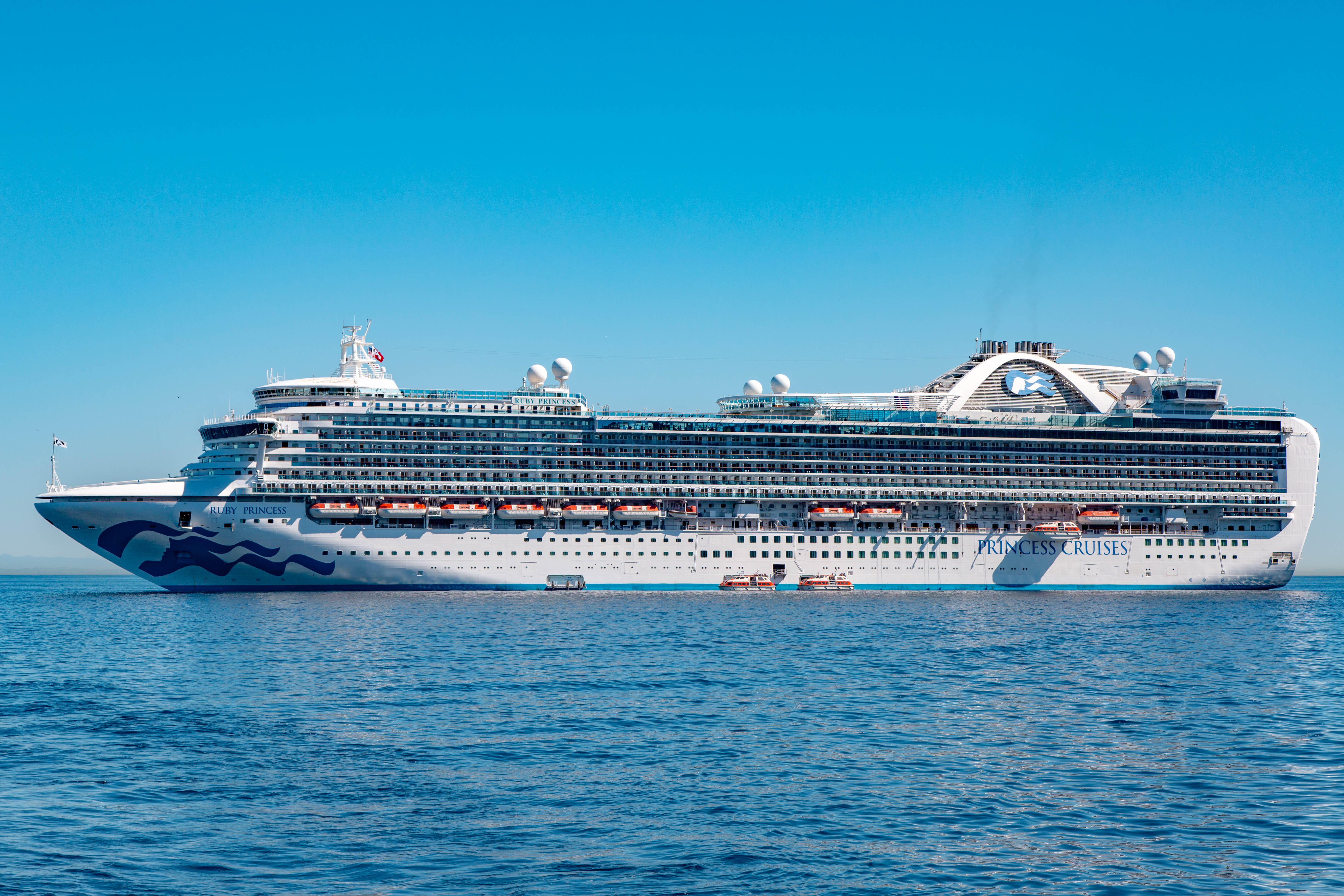 The Ruby Princess cruise ship sailing on the ocean on a clear, sunny day.