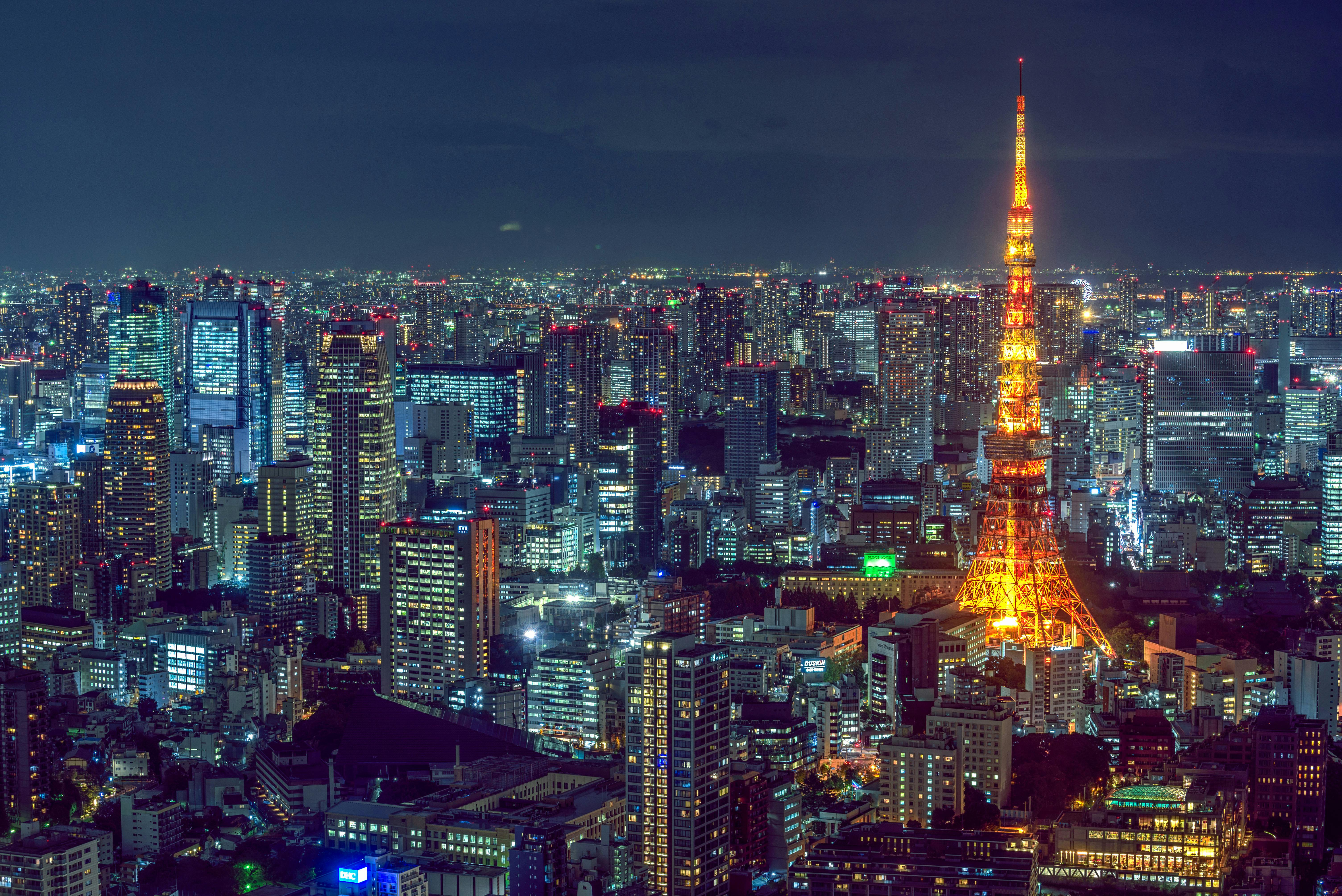 Night cityscape with illuminated tower and skyscrapers.