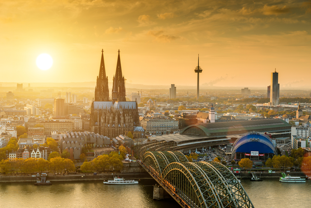 Aerial view of a city with a large cathedral and a bridge over a river at sunset.