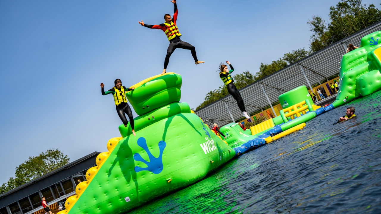 People jumping on an inflatable water obstacle course.