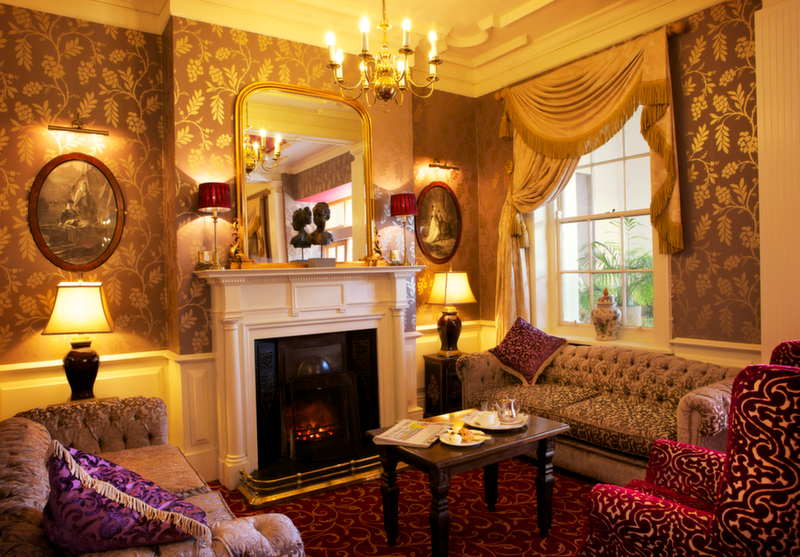 An elegantly decorated sitting room with plush furniture, a fireplace, and warm, ambient lighting.