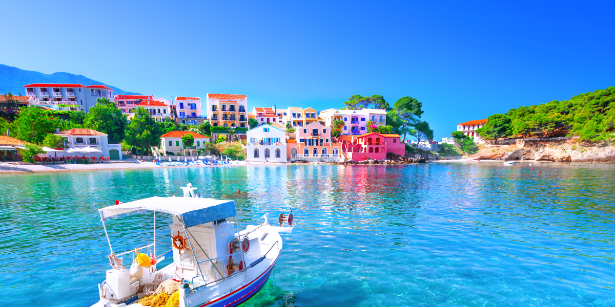 Colorful seaside village with a boat in clear blue water.