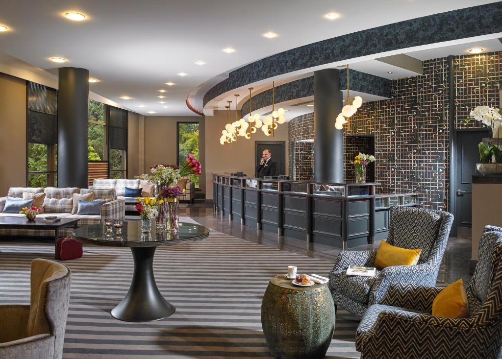 A stylish hotel lobby with a reception desk, a seating lounge, and a concierge on the phone.