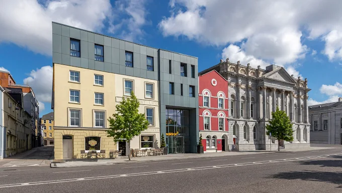 Street view of modern and classical buildings under a blue sky with clouds.