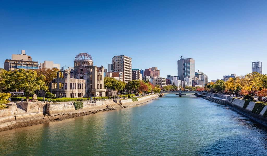 River with city skyline and historic dome building under clear blue sky.