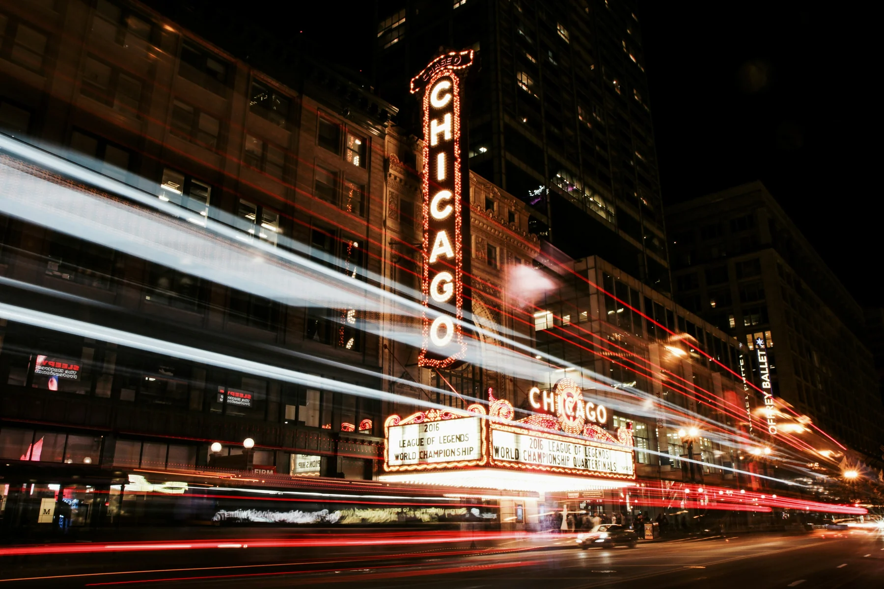 Night view of Chicago Theater with light trails from passing vehicles.