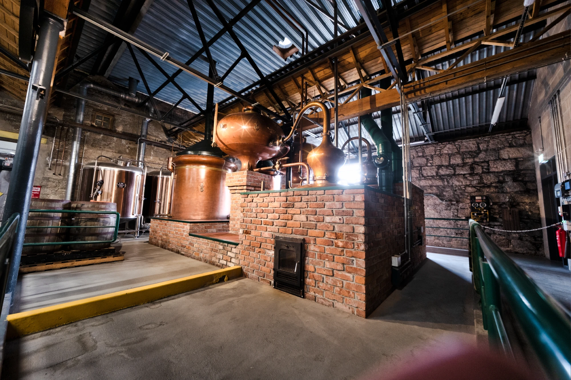 Interior of a distillery with copper stills and brick walls.