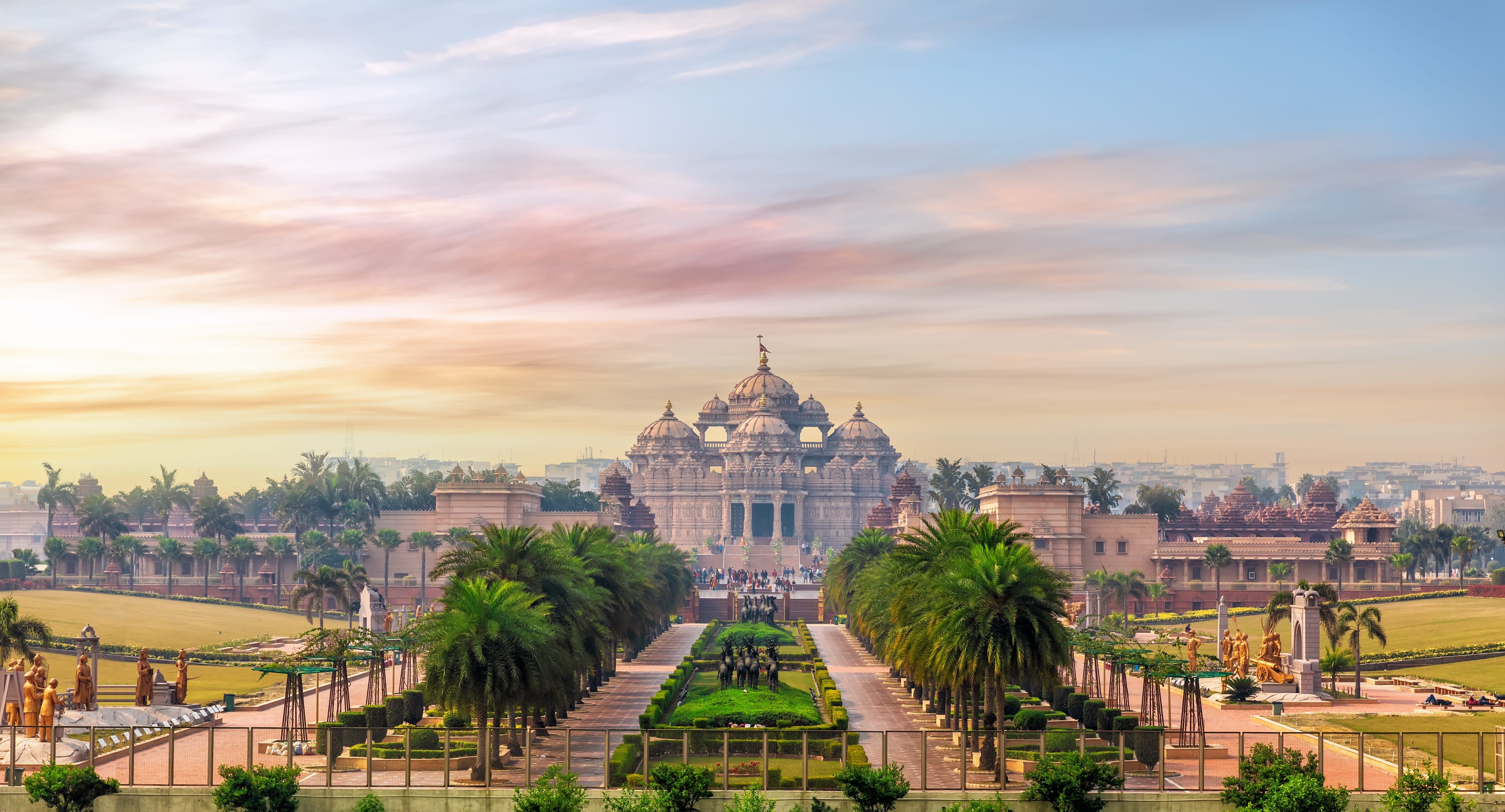 Ornate temple with multiple domes surrounded by gardens and statues.
