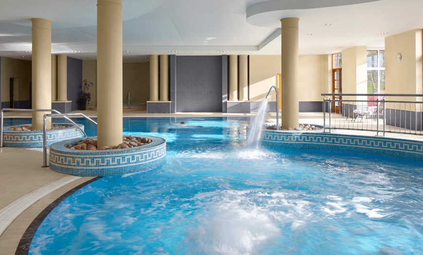 Indoor swimming pool with columns and water features.