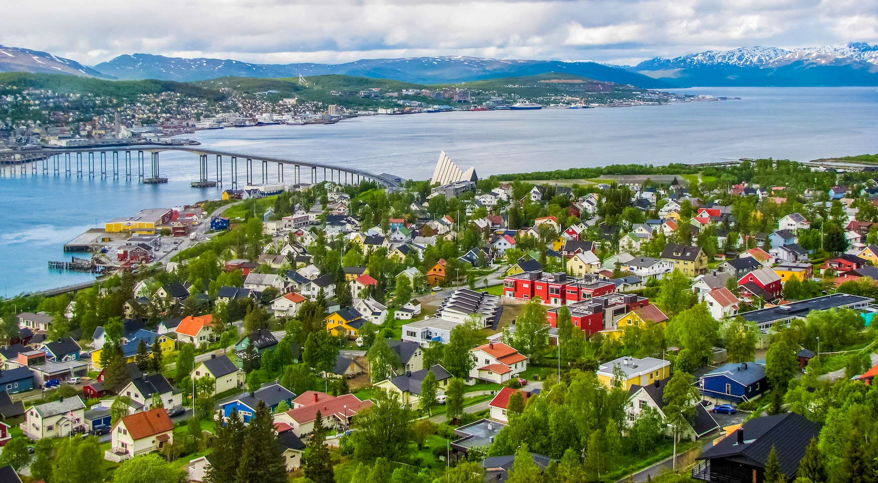 Aerial view of a coastal town with colorful houses and a bridge.