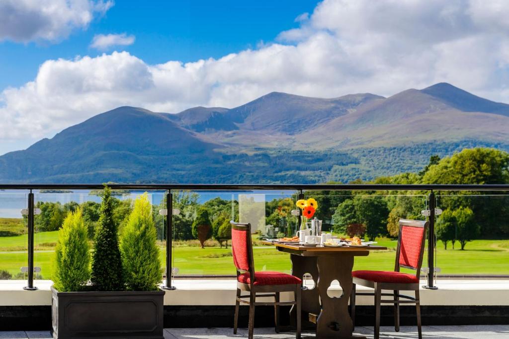 Outdoor dining table with red chairs, mountain view, and clear blue sky.