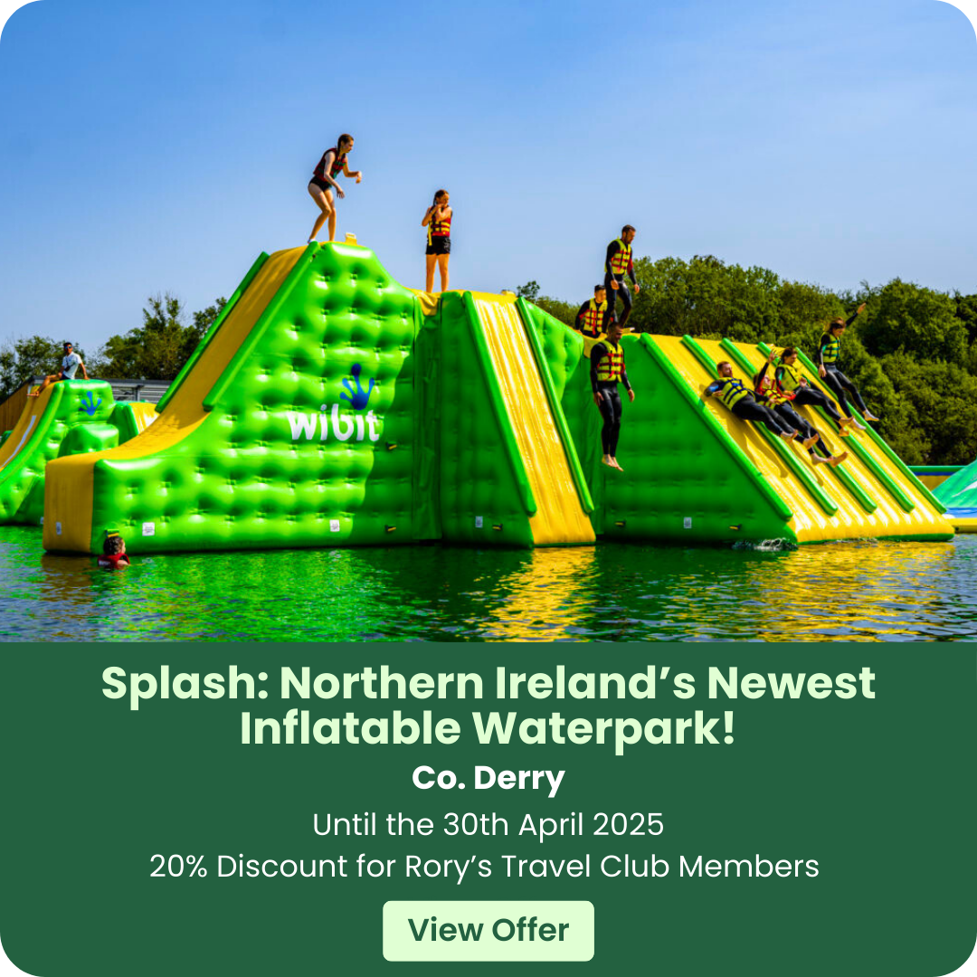 People enjoying an inflatable waterpark with slides and climbing structures on a sunny day.