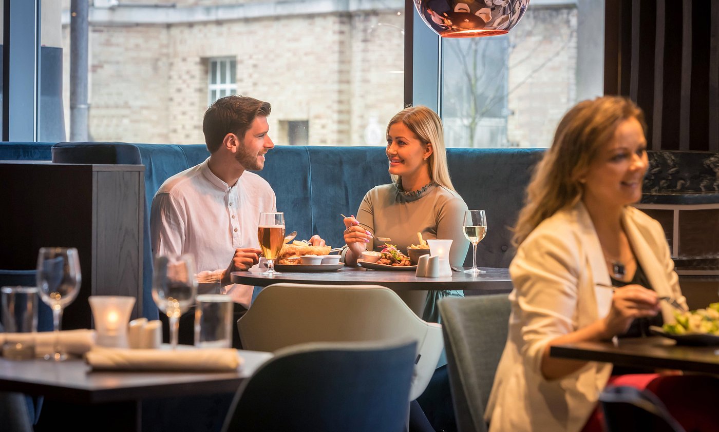 Two people dining at a restaurant, smiling and talking.
