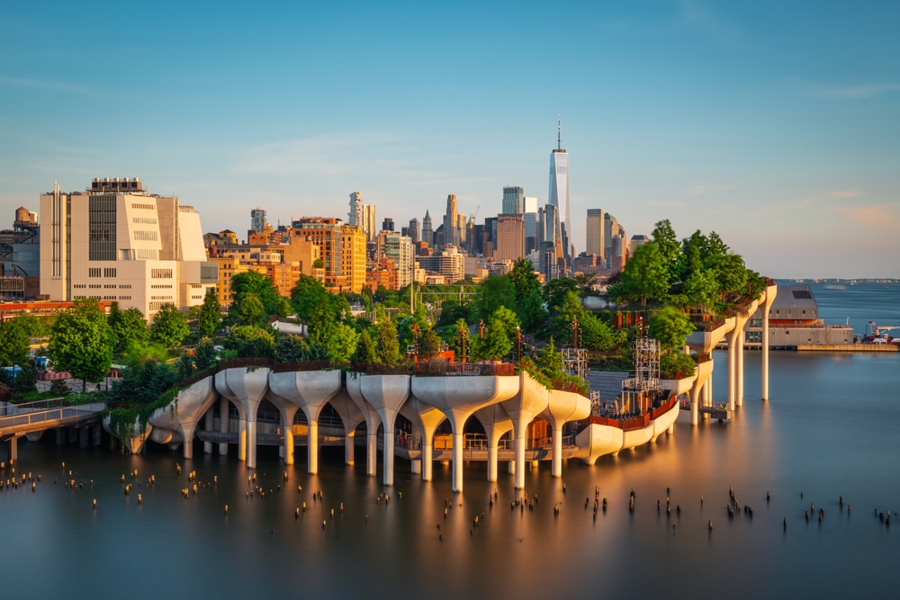 Little Island park on the Hudson River with the New York City skyline in the background at sunset.