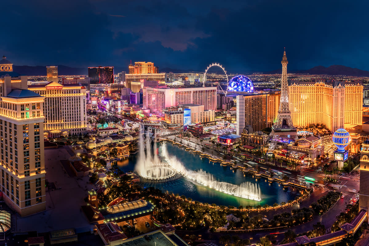 An elevated view of the brightly illuminated Las Vegas Strip at night, with hotels and fountains.