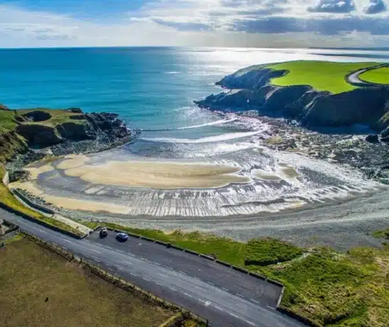 Aerial view of a coastal bay with sandy beach and cliffs.
