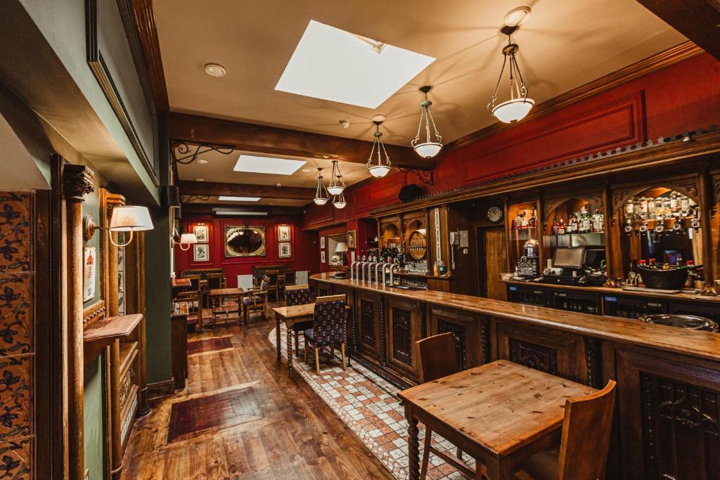 The interior of a traditional, empty pub with an ornate wooden bar and tables.