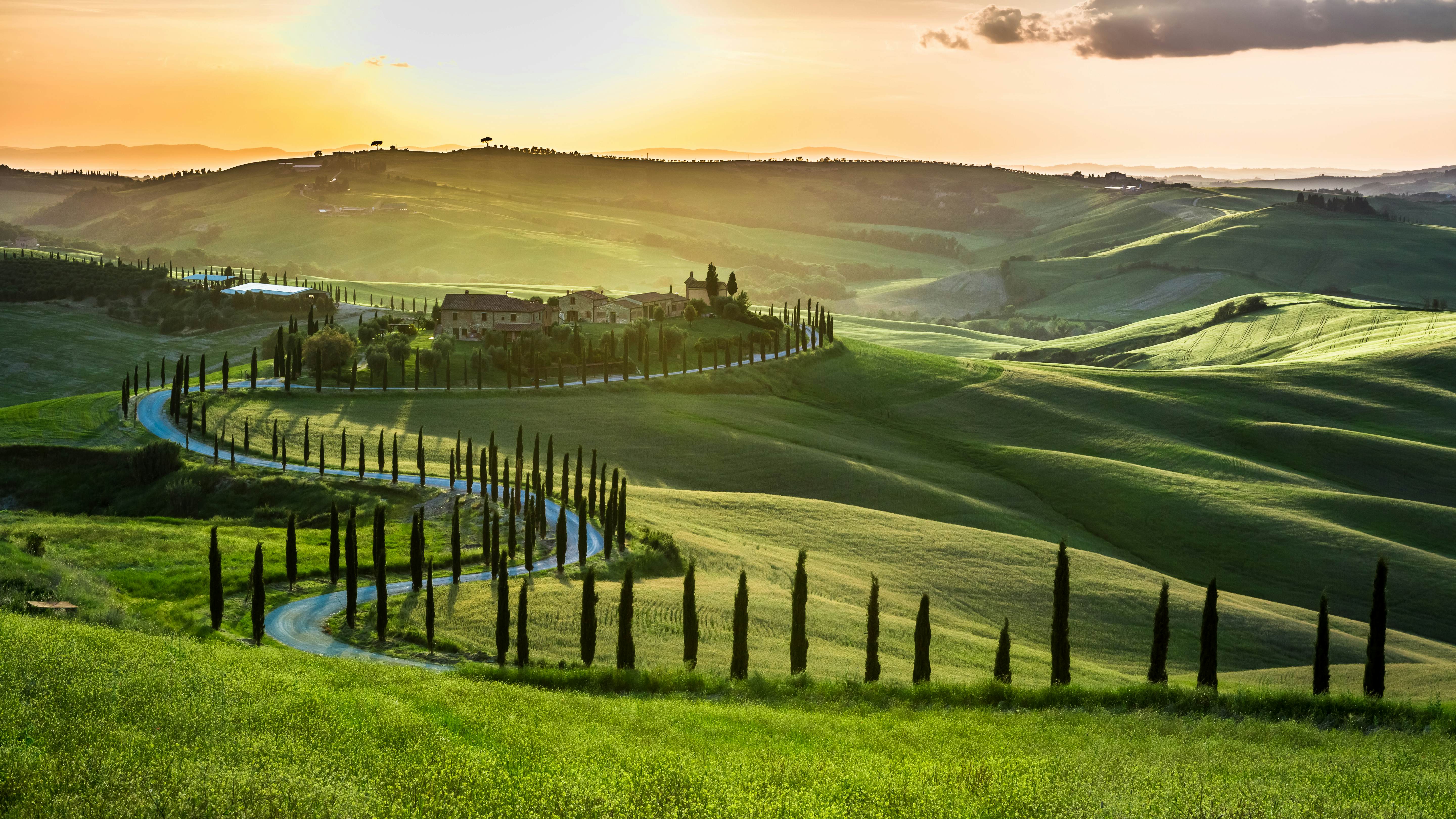 Sunset over rolling hills and winding road in the countryside.