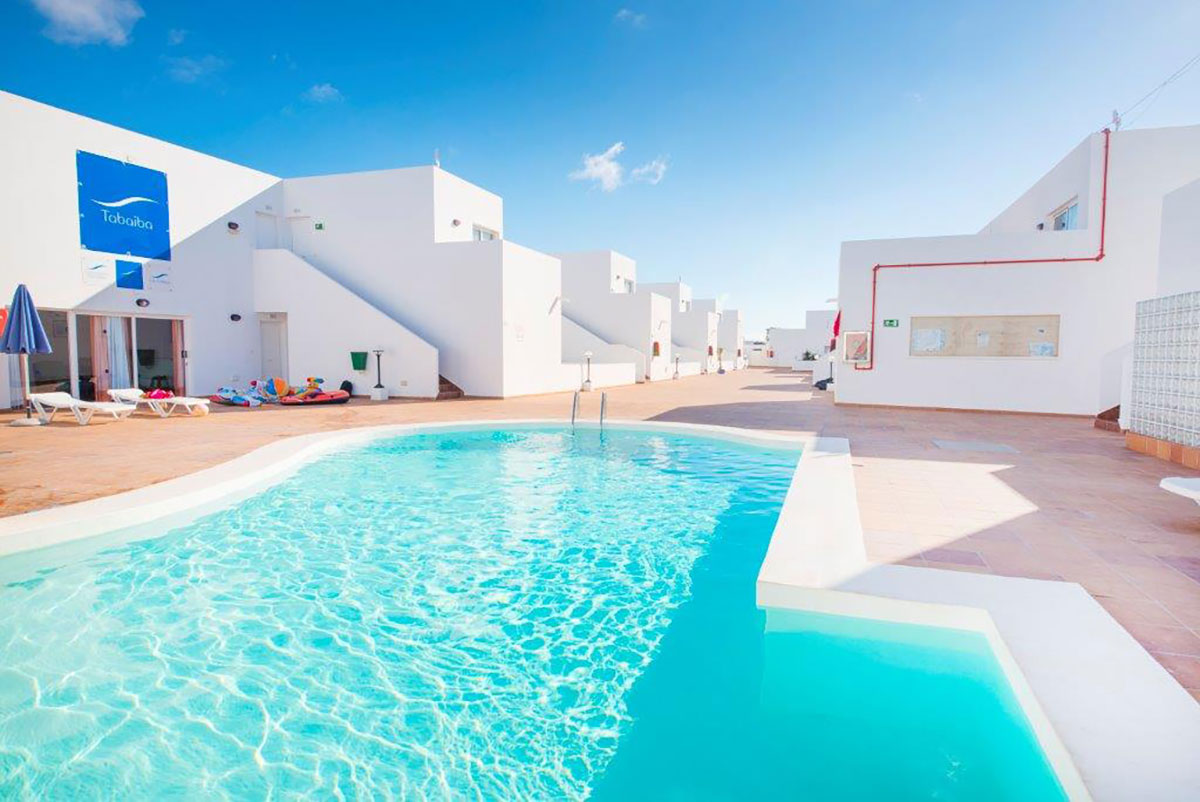 Outdoor pool with white buildings and clear blue sky.