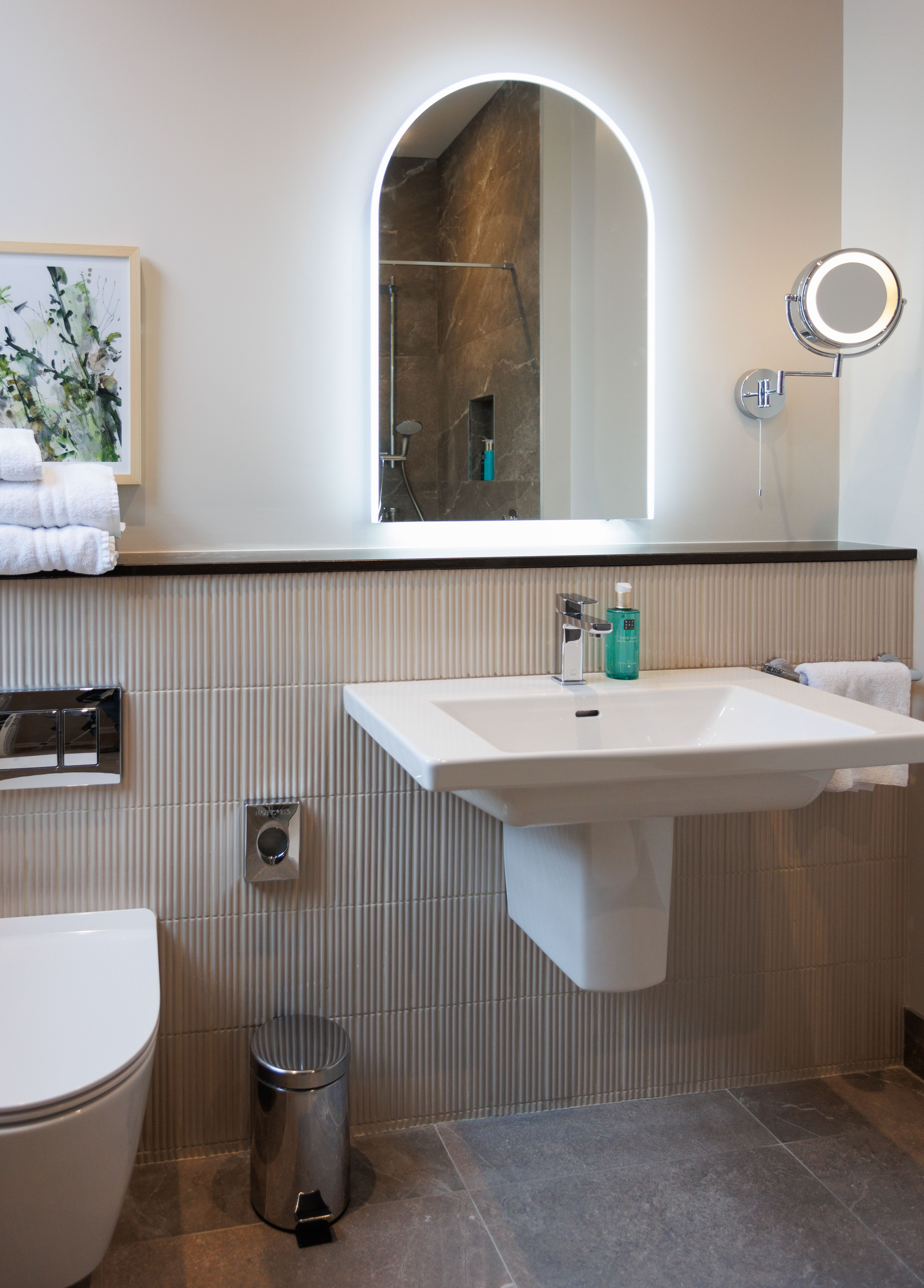 Modern bathroom with illuminated mirror, sink, and shower area.