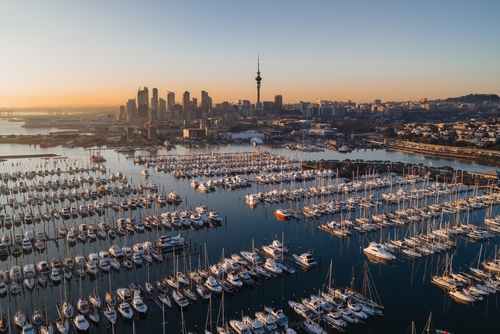 Aerial view of a large marina filled with boats, with a city skyline in the background at sunrise.