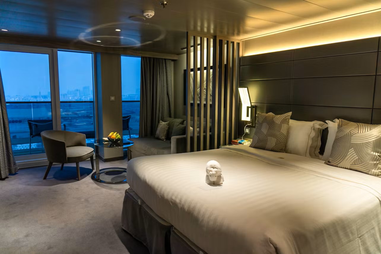 Modern hotel room with a large bed, seating area, and city view.