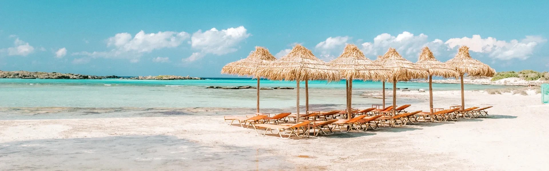 Beach with straw umbrellas and lounge chairs by the sea.