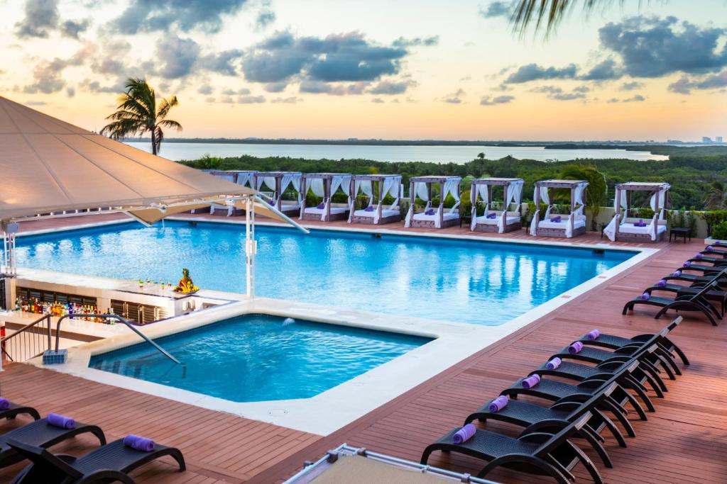Outdoor pool area with lounge chairs and cabanas at sunset.