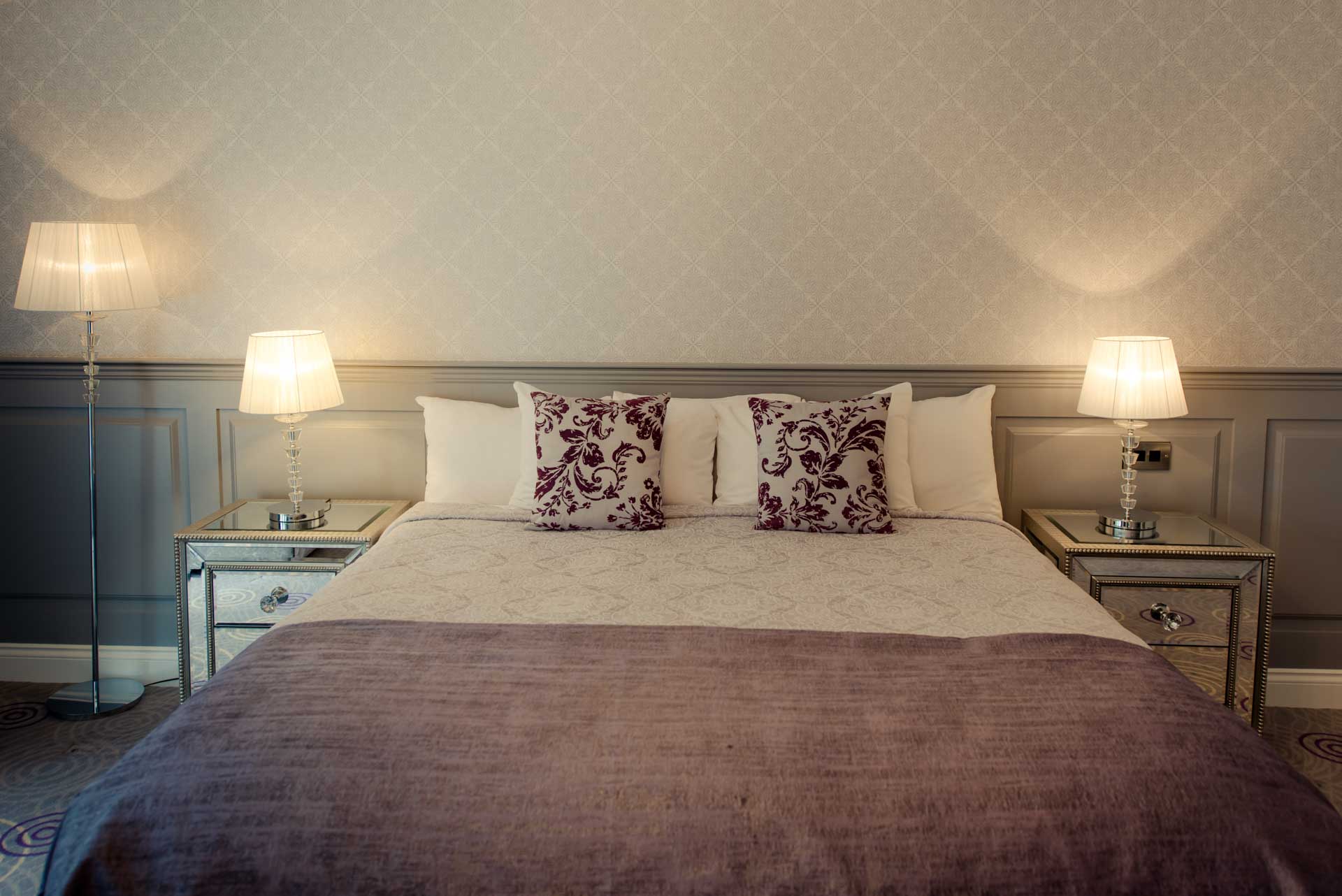 Hotel room with a large bed, two chairs, and a wall-mounted TV.