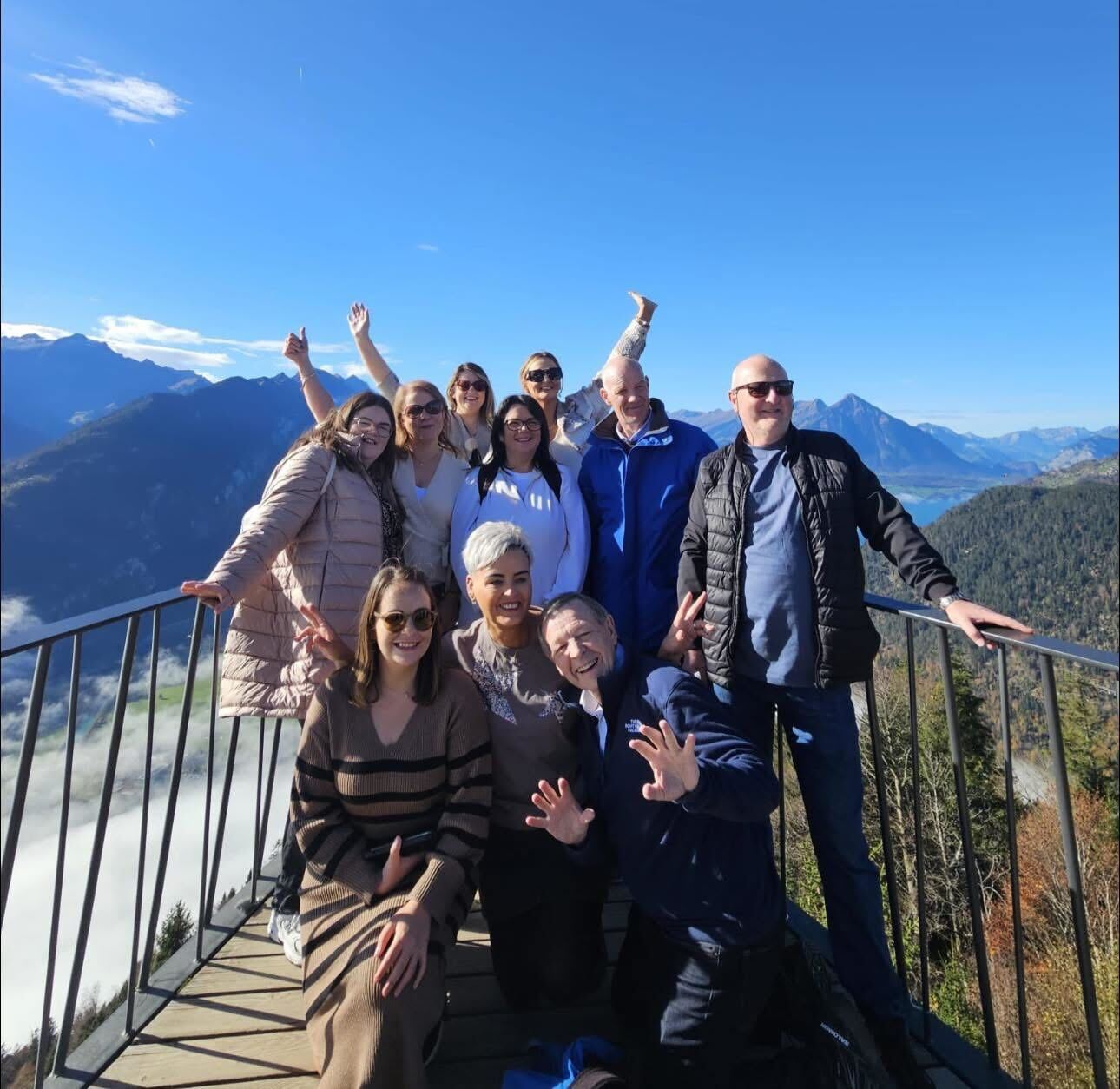 Group of people posing on a mountain viewpoint with scenic background.