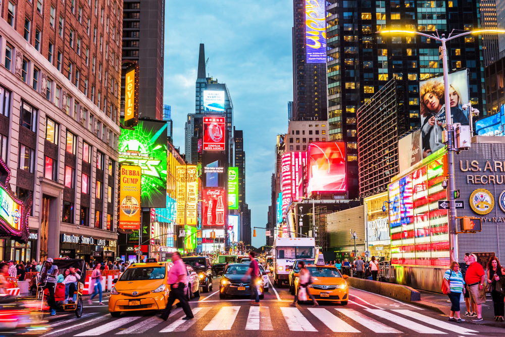 Times Square at night with bright billboards and busy street.