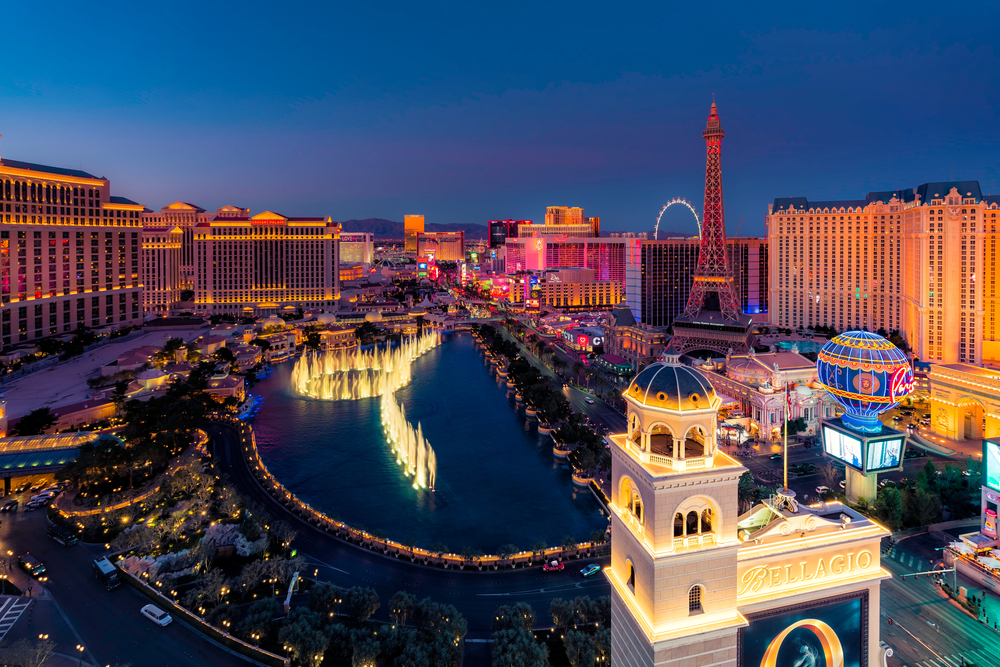 Aerial view of the Las Vegas strip at dusk, featuring the Bellagio fountains and the Paris Las Vegas hotel.
