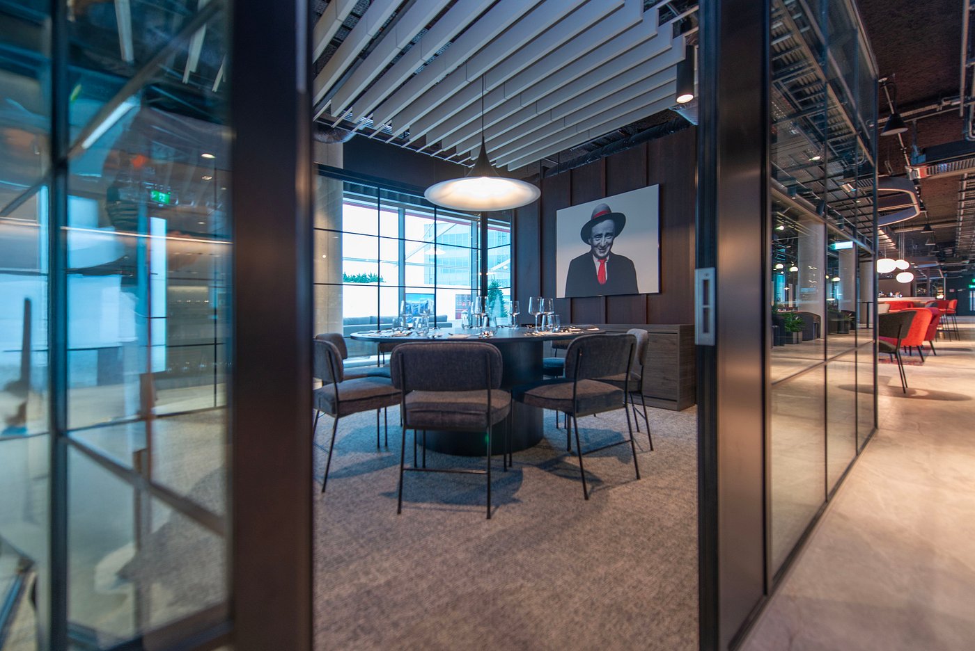 Modern conference room with a round table, chairs, and a portrait on the wall.