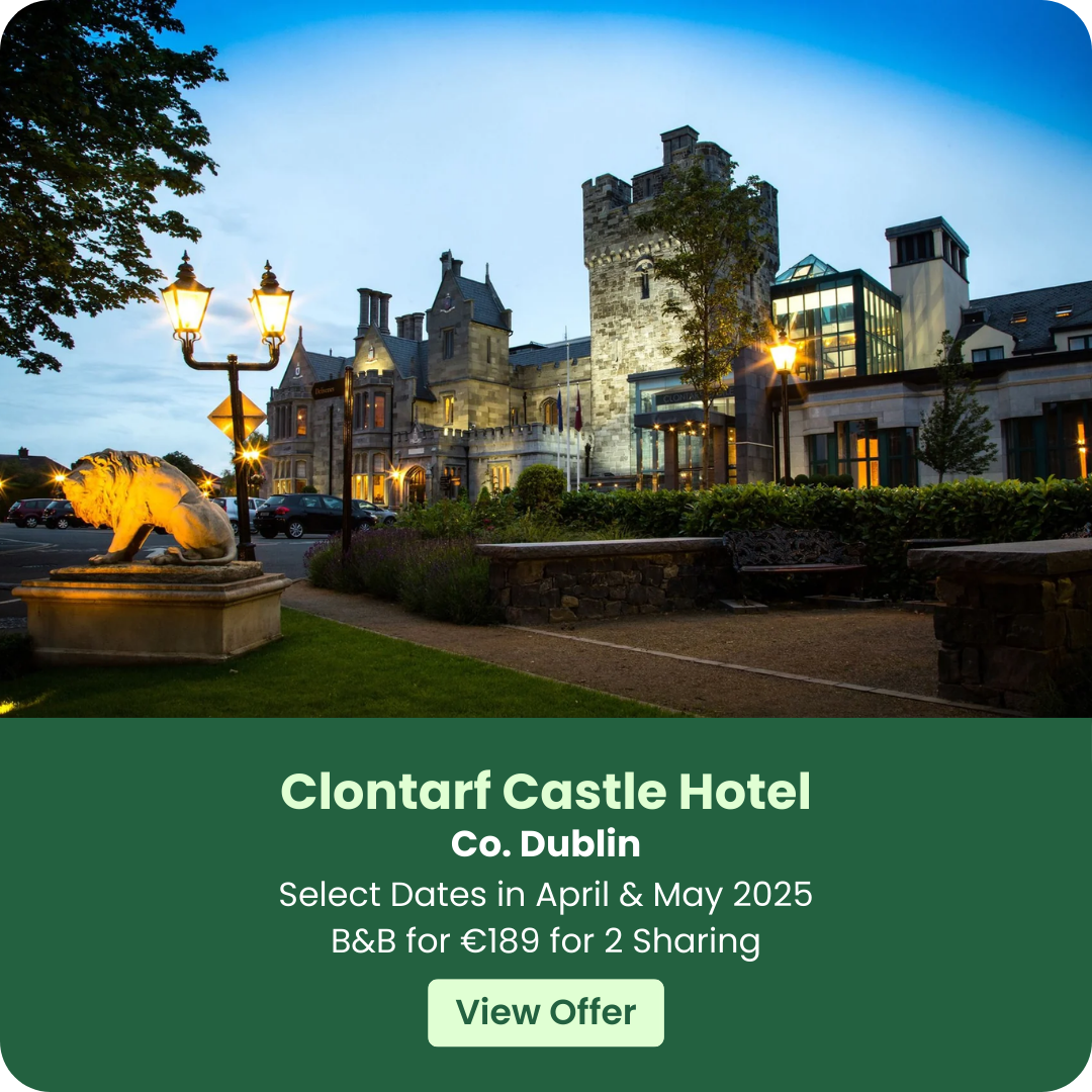 Clontarf Castle Hotel exterior at dusk with illuminated street lamps and a lion statue.