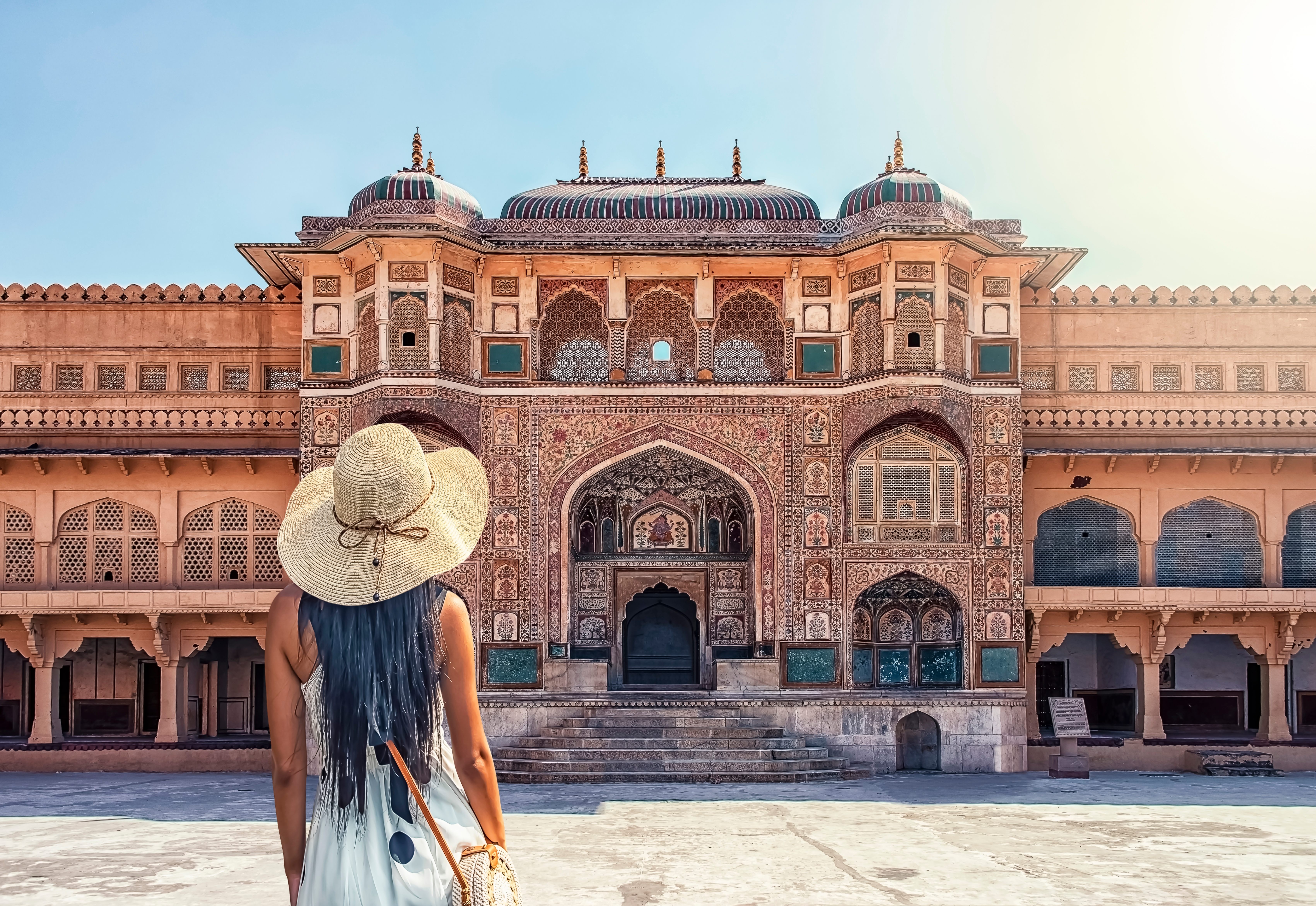 Woman in hat standing before ornate historical building.