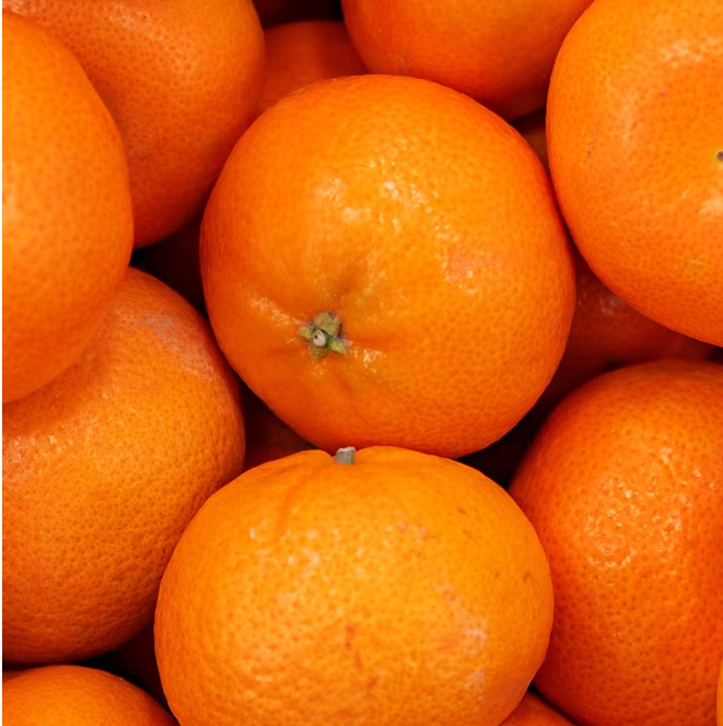 A pile of fresh, orange tangerines closely packed together.