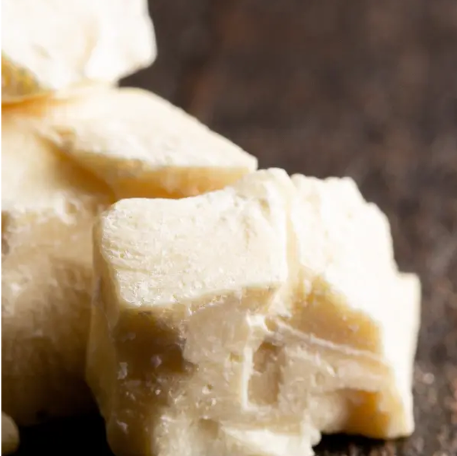 Chunks of natural cocoa butter on a wooden surface.