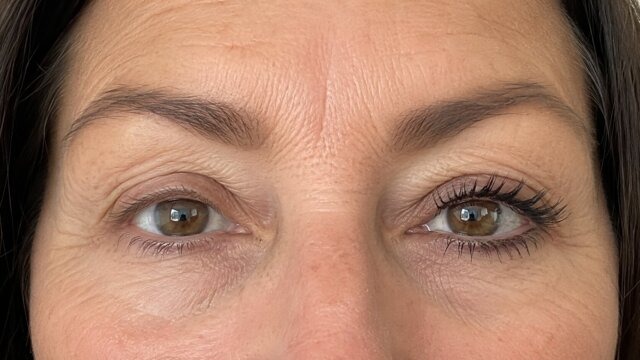 A close-up of a woman's eyes, with mascara applied to one eye and not the other.