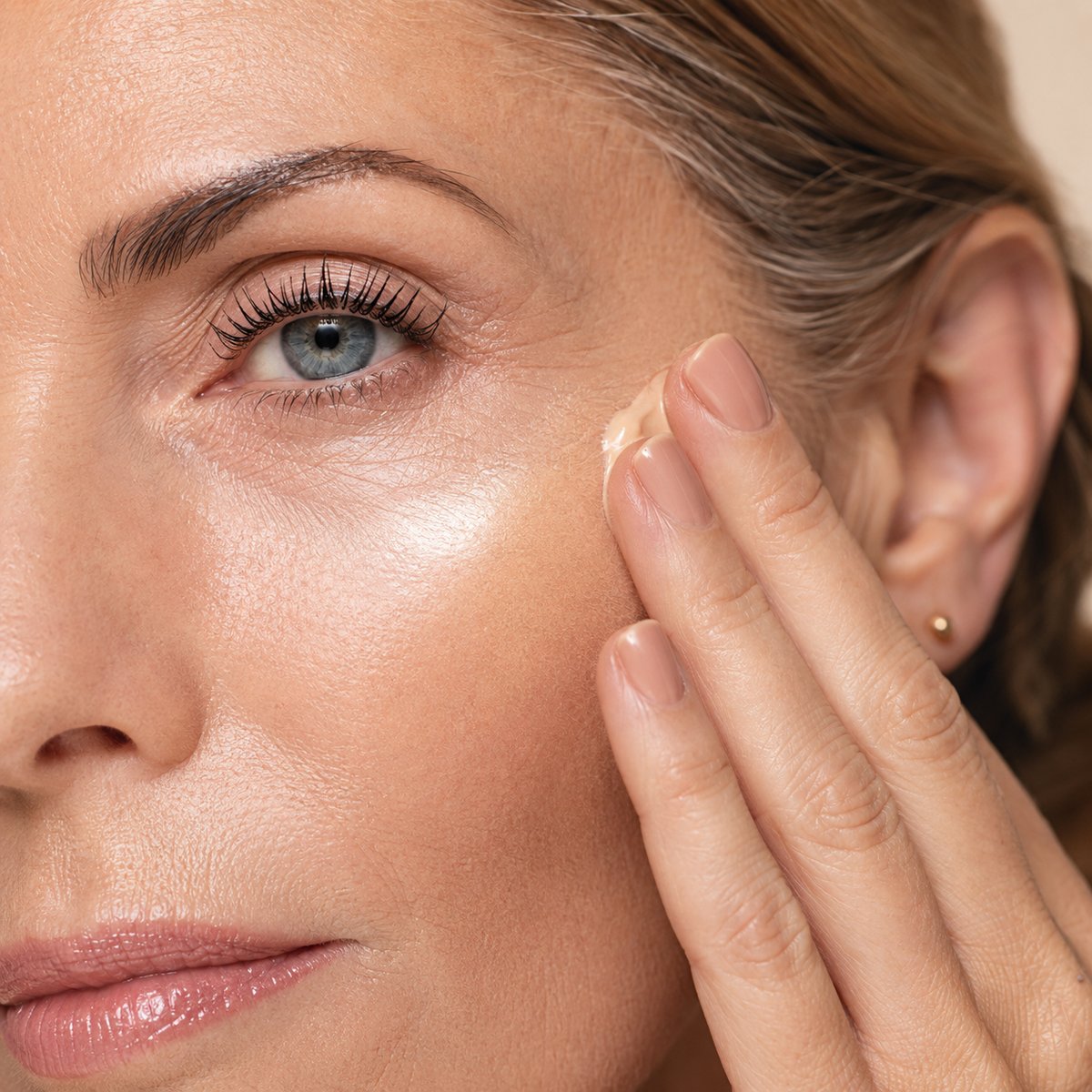 Woman applying cream makeup to her cheek