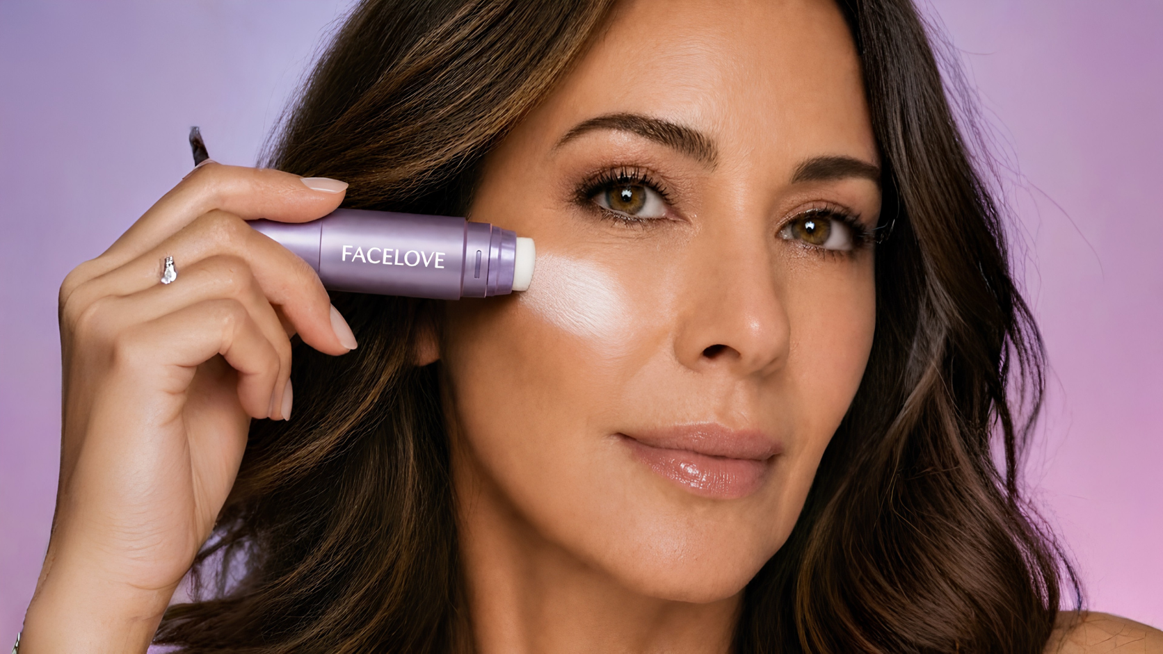 A woman with brown hair applies a purple highlighter stick labeled FACELOVE to her cheekbone.
