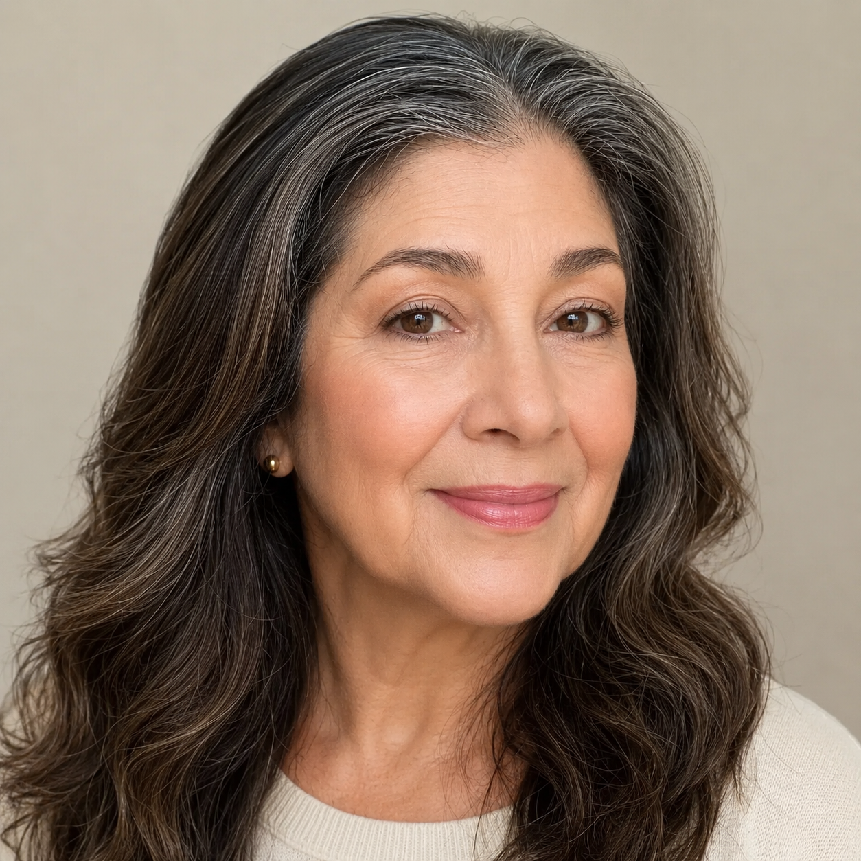 A headshot of a woman with long, salt-and-pepper hair, smiling slightly at the camera.