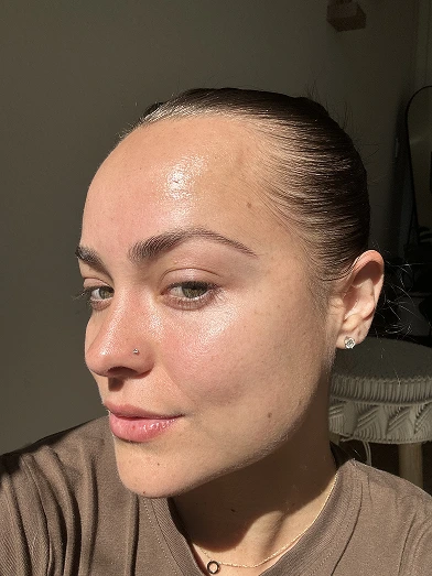 Close-up of a person with a nose piercing and earrings in natural light.