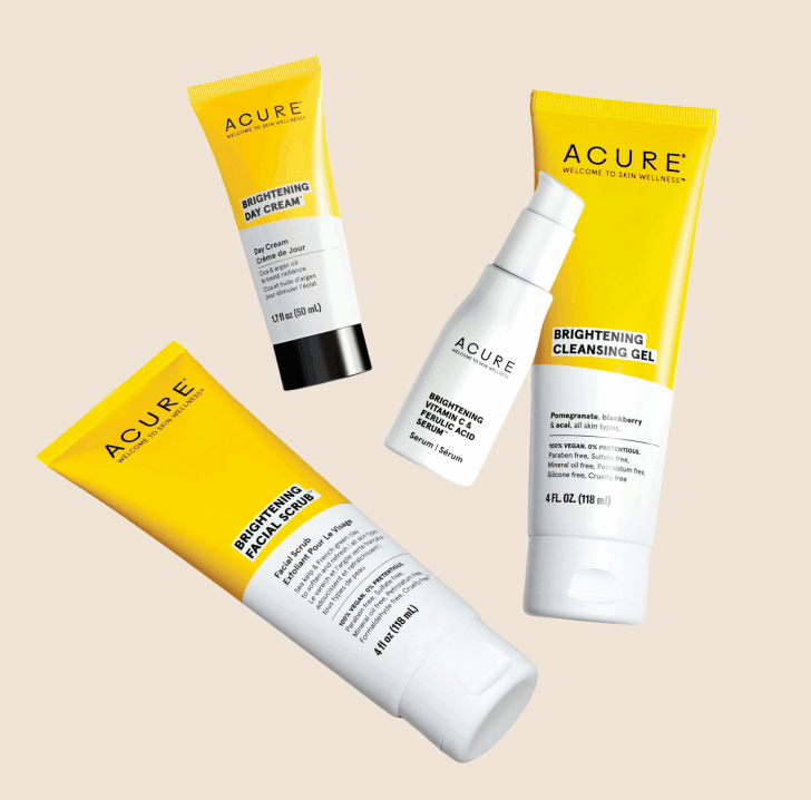 Four skincare products with yellow and white packaging on a beige background.