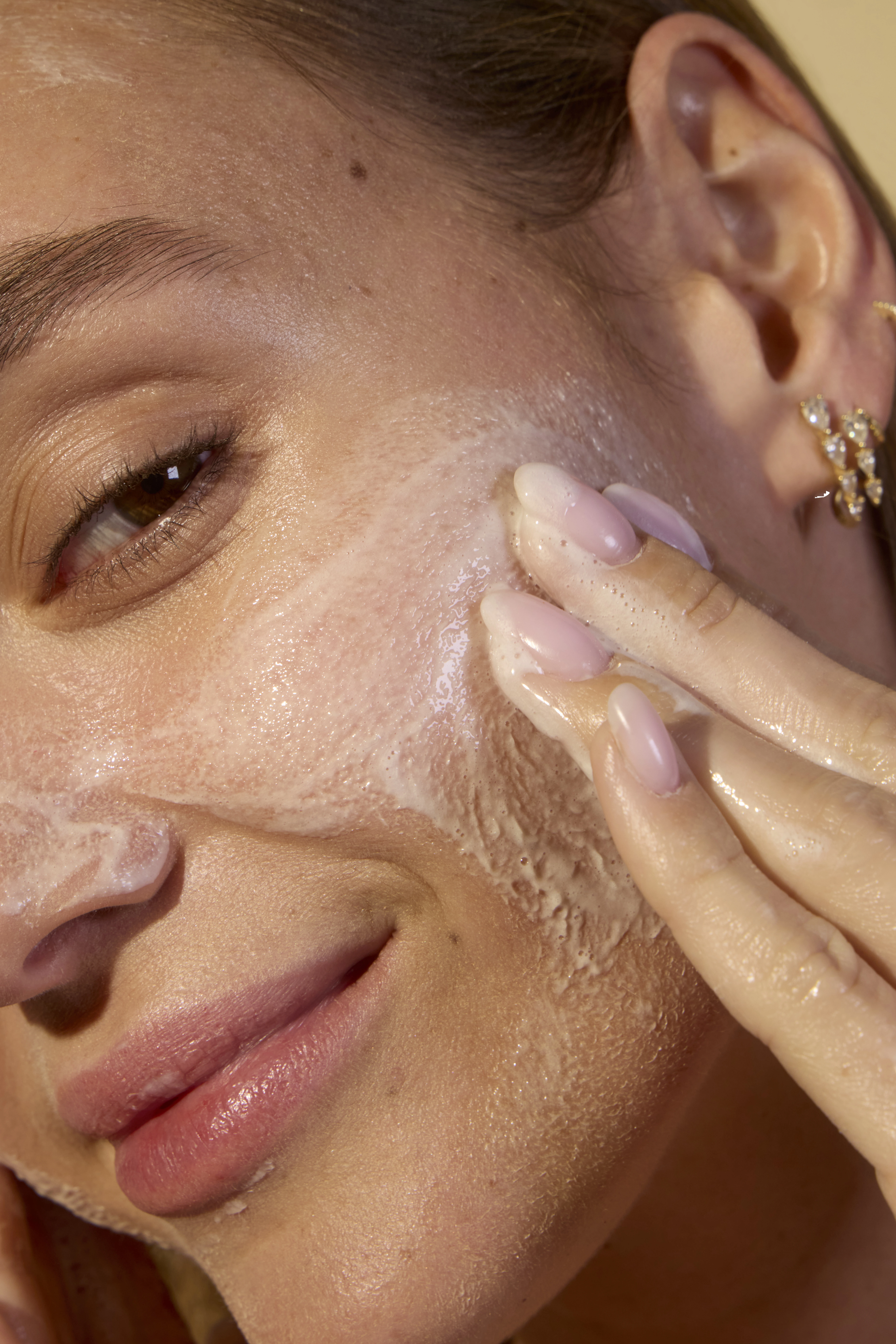 A person holds Acure brightening facial scrub tube with usage statistics.